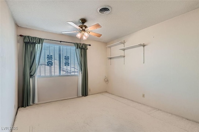 spare room featuring visible vents, a ceiling fan, light carpet, and a textured ceiling