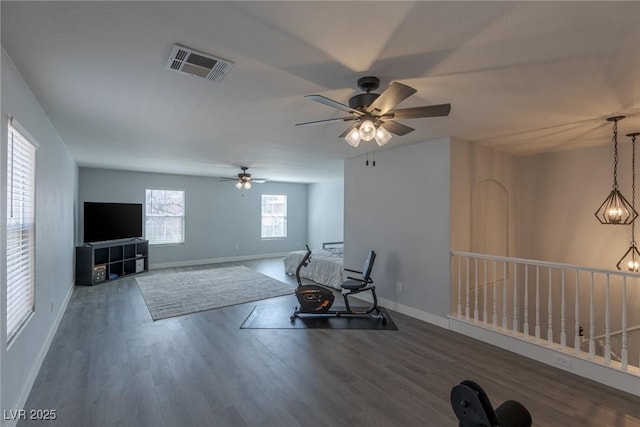 living area featuring visible vents, baseboards, ceiling fan, and wood finished floors