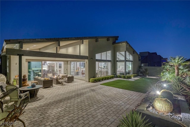 10271 Meridian Hill Ave, Las Vegas, NV 89135 - back of house at night featuring stucco siding, outdoor lounge area, and a patio area