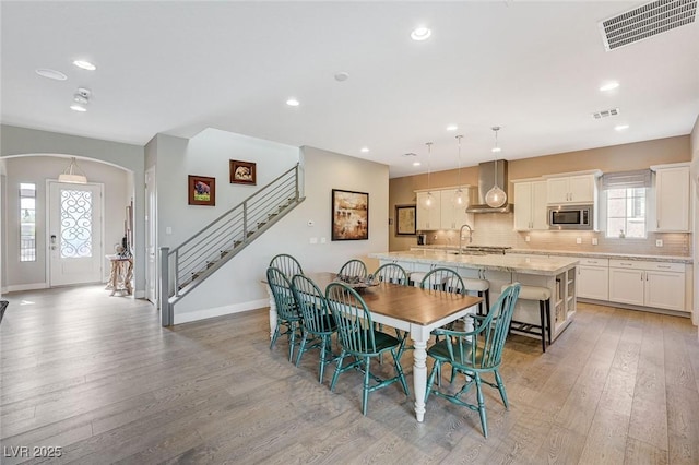 10840 Rosin Jaw St, Las Vegas, NV 89183 - dining space featuring visible vents, light wood-type flooring, arched walkways, and stairway