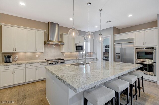 10840 Rosin Jaw St, Las Vegas, NV 89183 - kitchen with white cabinets, wall chimney exhaust hood, built in appliances, a sink, and light wood-style flooring