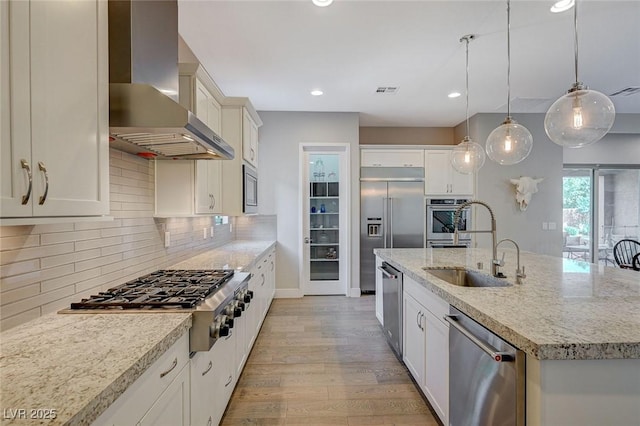 10840 Rosin Jaw St, Las Vegas, NV 89183 - kitchen featuring light wood-style floors, wall chimney exhaust hood, a sink, built in appliances, and backsplash