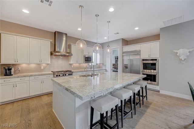 10840 Rosin Jaw St, Las Vegas, NV 89183 - kitchen featuring built in appliances, wall chimney range hood, an island with sink, white cabinetry, and a sink