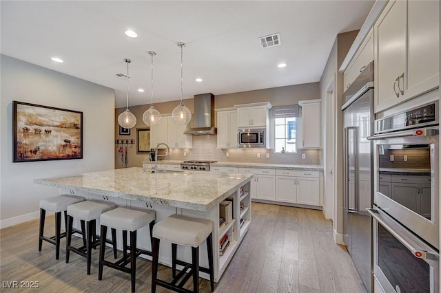 10840 Rosin Jaw St, Las Vegas, NV 89183 - kitchen featuring tasteful backsplash, wall chimney range hood, visible vents, appliances with stainless steel finishes, and a sink