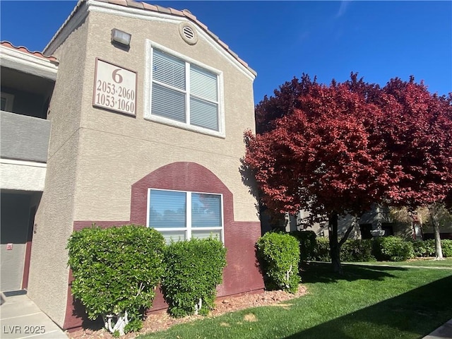 5055 W Hacienda Ave Unit 2055, Las Vegas, NV 89118 - view of side of home with stucco siding, a tiled roof, and a yard