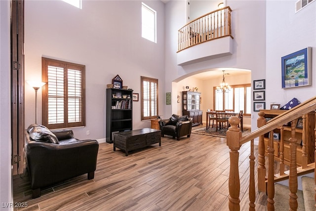 7416 Redhead Dr, North Las Vegas, NV 89084 - living area with arched walkways, a chandelier, wood finished floors, a towering ceiling, and baseboards