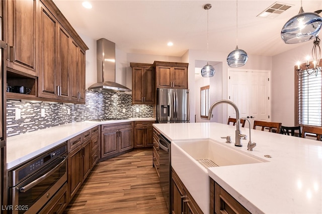 7416 Redhead Dr, North Las Vegas, NV 89084 - kitchen with appliances with stainless steel finishes, wall chimney range hood, a sink, wood finished floors, and decorative backsplash