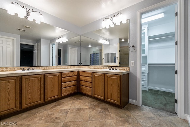 7416 Redhead Dr, North Las Vegas, NV 89084 - bathroom with double vanity, a walk in closet, tasteful backsplash, and stone finish flooring