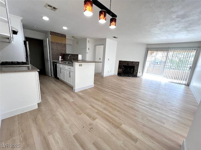 kitchen with light wood finished floors, white cabinetry, and visible vents