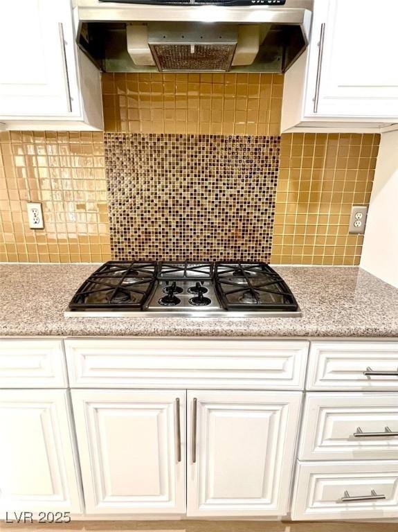kitchen featuring wall chimney exhaust hood, white cabinets, tasteful backsplash, and stainless steel gas stovetop