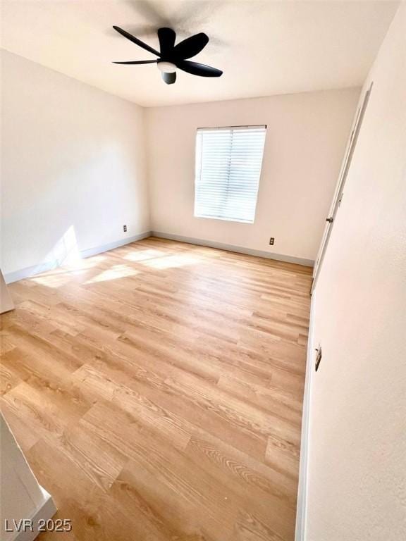 spare room featuring baseboards, light wood-style flooring, and ceiling fan