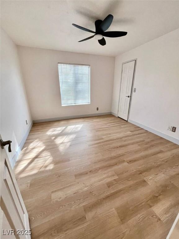 empty room featuring baseboards, a ceiling fan, and light wood finished floors