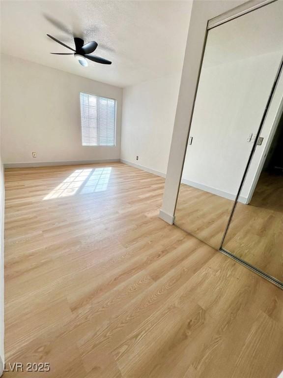 unfurnished bedroom featuring light wood-type flooring, a ceiling fan, and baseboards