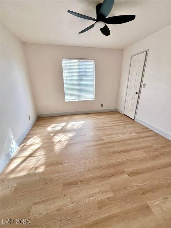 unfurnished room with baseboards, ceiling fan, and light wood-style flooring