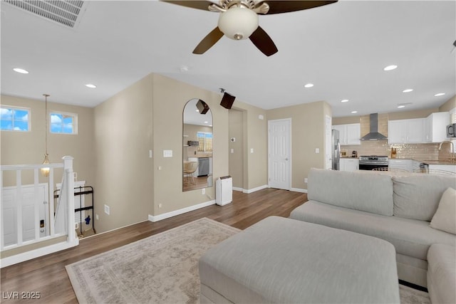 living area featuring a ceiling fan, wood finished floors, baseboards, visible vents, and recessed lighting