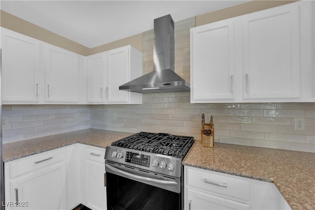 kitchen featuring wall chimney range hood, white cabinets, stainless steel gas range, and backsplash
