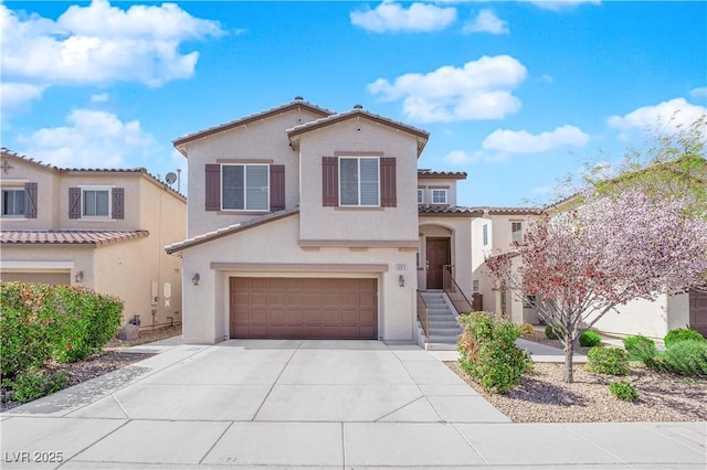 mediterranean / spanish home featuring stucco siding, a garage, a tiled roof, and concrete driveway