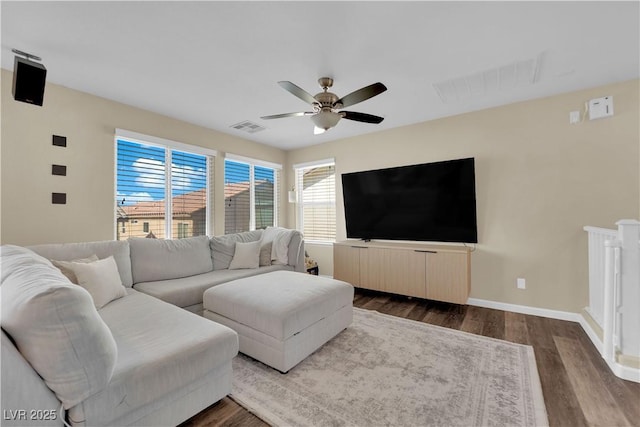 living area featuring dark wood finished floors, baseboards, ceiling fan, and visible vents