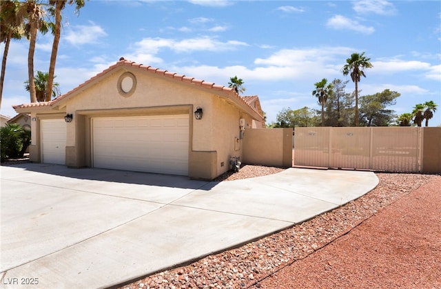 5217 Cold River Ave, Las Vegas, NV 89130 - view of side of property featuring stucco siding, a gate, driveway, an attached garage, and a tile roof
