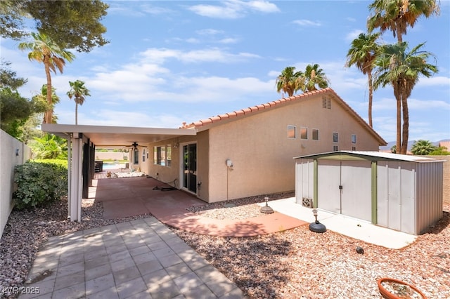 5217 Cold River Ave, Las Vegas, NV 89130 - view of side of home featuring stucco siding, a tile roof, a storage shed, and ceiling fan