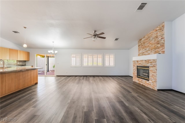 5217 Cold River Ave, Las Vegas, NV 89130 - unfurnished living room featuring a chandelier, vaulted ceiling, a ceiling fan, a fireplace, and healthy amount of natural light