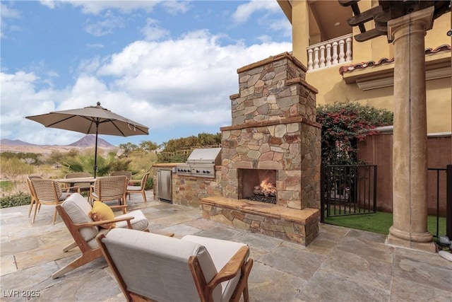 15 Rue Du Rivoli Pl, Henderson, NV 89011 - view of patio / terrace with a mountain view, exterior kitchen, and an outdoor stone fireplace