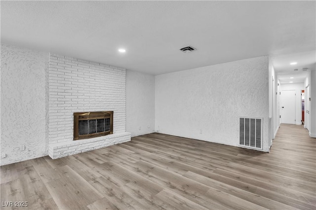 2204 Monterey Ave, Las Vegas, NV 89104 - unfurnished living room featuring a textured wall, a fireplace, wood finished floors, and recessed lighting