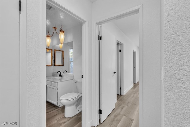 2204 Monterey Ave, Las Vegas, NV 89104 - bathroom featuring wood finished floors, toilet, vanity, and a textured wall