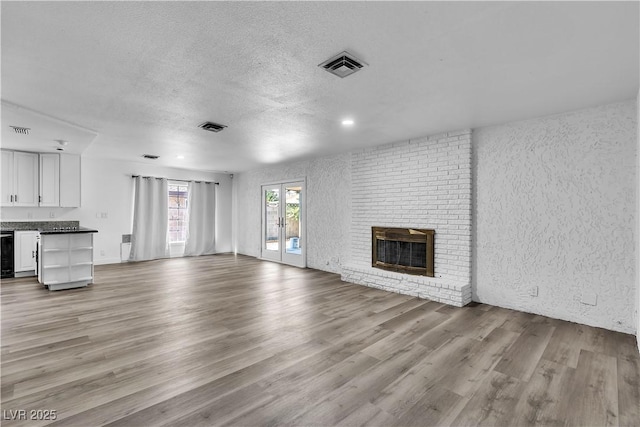2204 Monterey Ave, Las Vegas, NV 89104 - unfurnished living room with light wood-style floors, a textured ceiling, a fireplace, and a textured wall