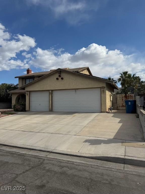 6801 Atwood Ave, Las Vegas, NV 89108 - view of front of home featuring stucco siding, driveway, a garage, and fence