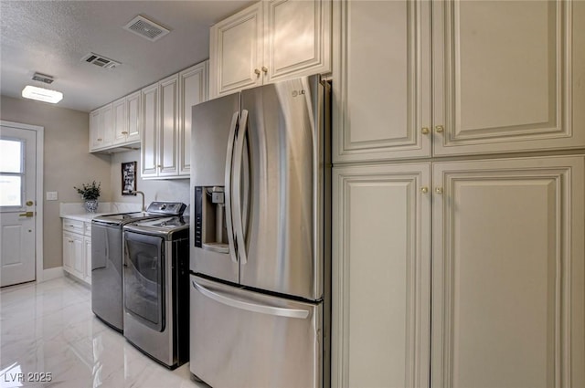 10550 Patrington Ct, Las Vegas, NV 89183 - kitchen featuring washer and clothes dryer, stainless steel fridge, visible vents, marble finish floor, and cream cabinets