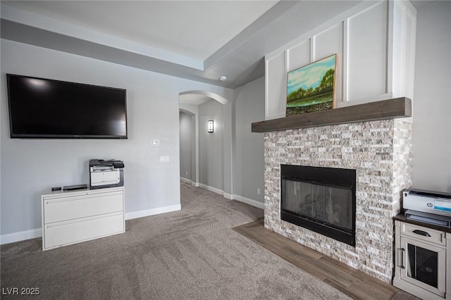 5815 Pristine Falls Ave, Las Vegas, NV 89131 - unfurnished living room with arched walkways, carpet, baseboards, and a glass covered fireplace