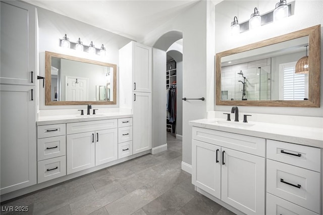 5815 Pristine Falls Ave, Las Vegas, NV 89131 - bathroom with a stall shower, two vanities, a spacious closet, and baseboards