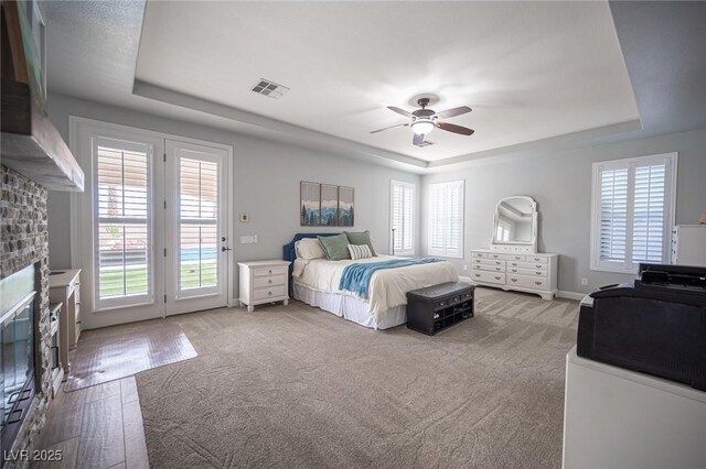 5815 Pristine Falls Ave, Las Vegas, NV 89131 - carpeted bedroom with a raised ceiling, access to exterior, a fireplace, and multiple windows
