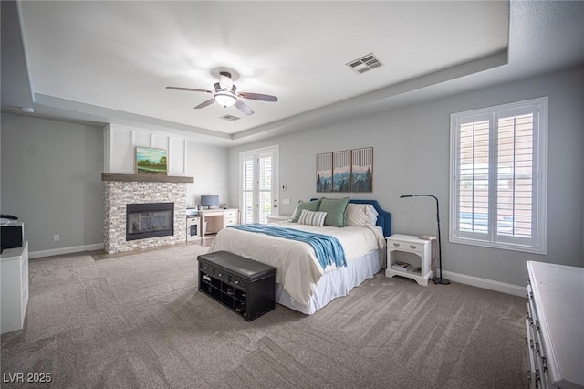 5815 Pristine Falls Ave, Las Vegas, NV 89131 - bedroom featuring a tray ceiling, carpet floors, baseboards, and a fireplace