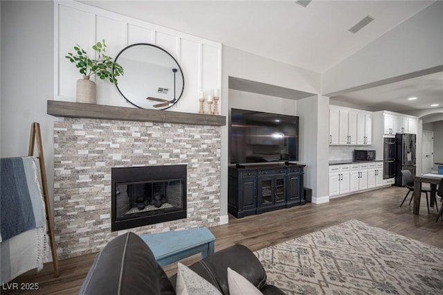 5815 Pristine Falls Ave, Las Vegas, NV 89131 - living area featuring lofted ceiling, a glass covered fireplace, wood finished floors, and arched walkways