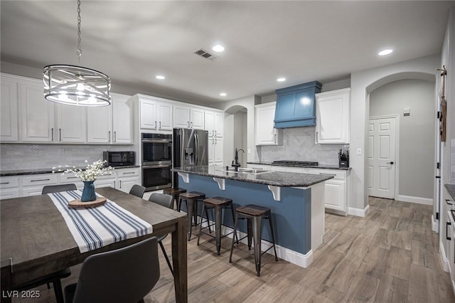 5815 Pristine Falls Ave, Las Vegas, NV 89131 - kitchen featuring a sink, arched walkways, appliances with stainless steel finishes, tasteful backsplash, and premium range hood