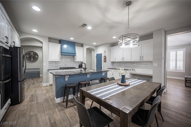 5815 Pristine Falls Ave, Las Vegas, NV 89131 - dining area featuring arched walkways, a chandelier, light wood finished floors, baseboards, and recessed lighting