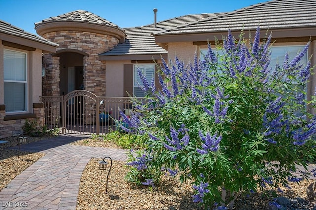 5815 Pristine Falls Ave, Las Vegas, NV 89131 - view of exterior entry with a tile roof, stone siding, stucco siding, and a gate