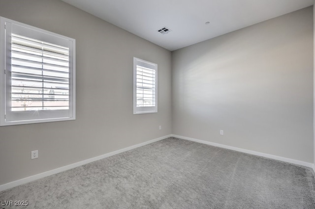 empty room featuring baseboards, visible vents, and carpet