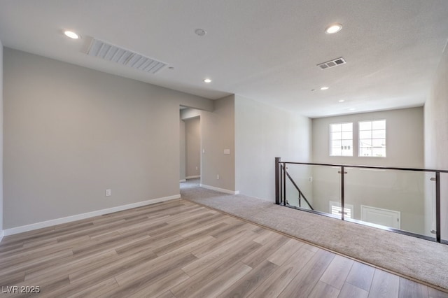 spare room with baseboards, recessed lighting, light wood-style floors, and visible vents
