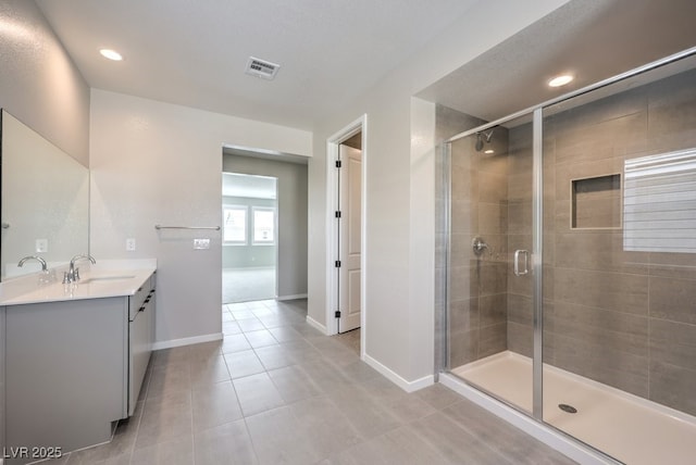 bathroom featuring vanity, visible vents, tile patterned floors, a shower stall, and baseboards