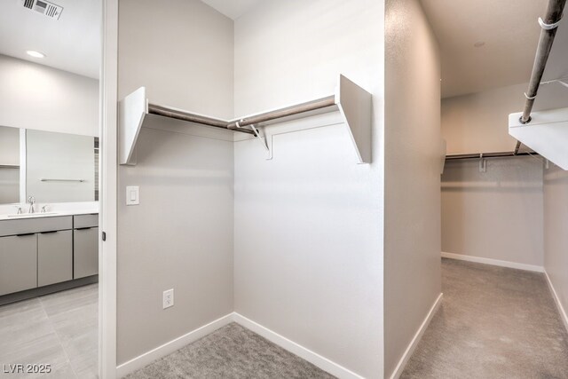spacious closet featuring a sink, light carpet, and visible vents
