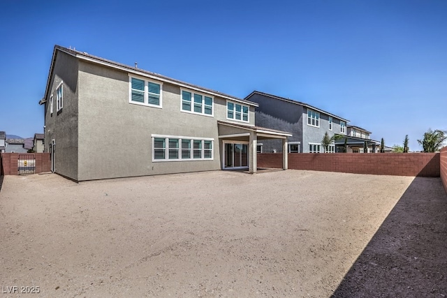 rear view of property featuring stucco siding and a fenced backyard