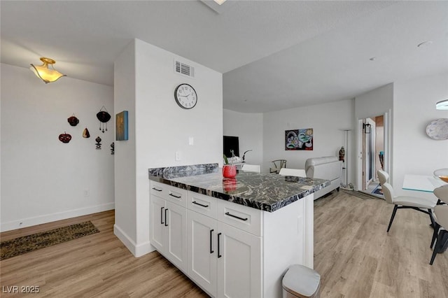 kitchen with white cabinetry, light wood-style flooring, a peninsula, and visible vents
