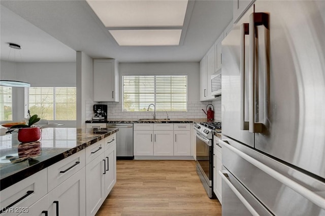 kitchen with tasteful backsplash, white cabinets, light wood-style floors, and stainless steel appliances