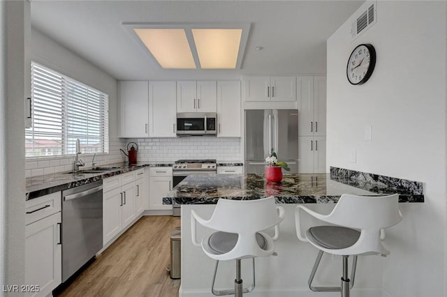 kitchen featuring a sink, stainless steel appliances, a kitchen breakfast bar, and tasteful backsplash