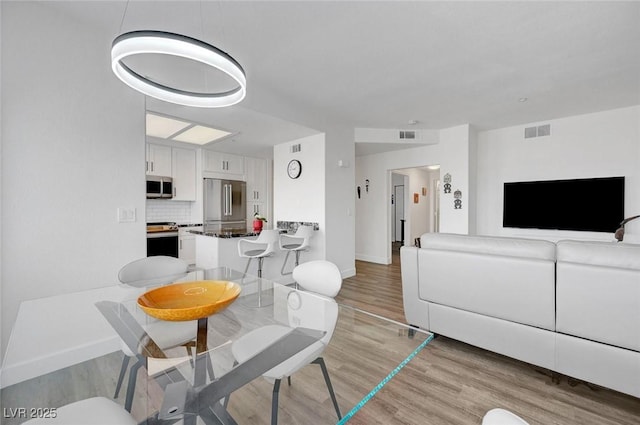 dining room with light wood-style flooring, baseboards, and visible vents