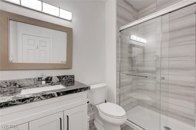 bathroom featuring a stall shower, toilet, and vanity