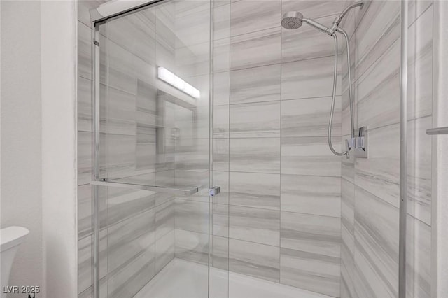 bathroom featuring toilet and a stall shower